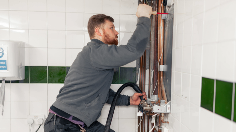 RJ Martindale engineer fixing central heating pipework in a kitchen, ready to install a boiler